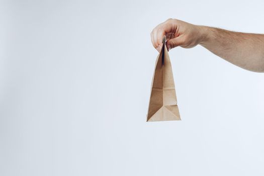 Courier hands giving packed food delivery close up against grey background