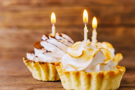 Birthday delicious cupcakes with candles on a wooden table, closeup.
