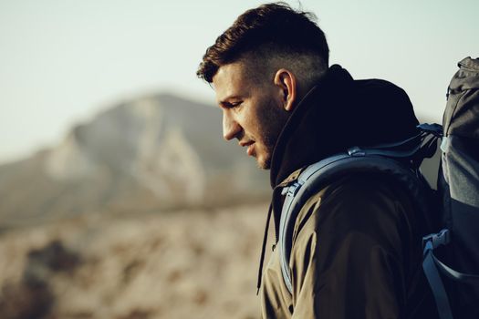 Young caucasian man traveler with big backpack hiking in the mountains alone