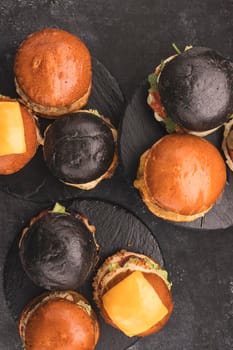 Many different burgers on dark, top view