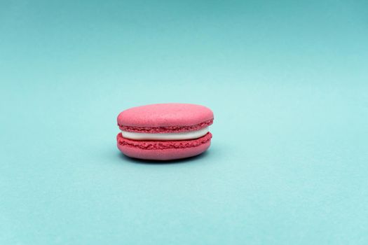 Pink strawberry macaroon on mint or turquoise background, copy space, almond cookies, pastel colors, no people.