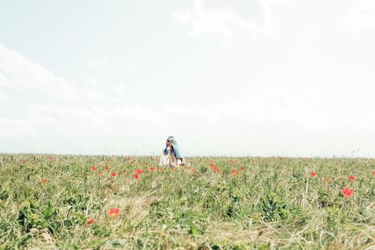 Beautiful young woman resting on meadow with red tulips in spring.