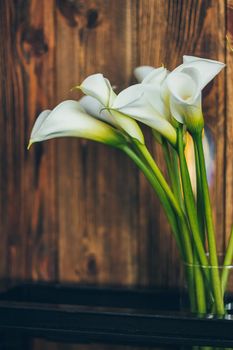 Still life with white callas on the rustic wooden background