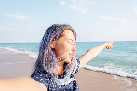 Young woman resting on beach vacations and pointing at the sea, point of view shot.