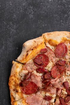 Four meat pizza with meat, sausage, ham and chicken on a dark concrete background