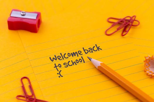 Back to School stationery and orange sheet of paper lie on the green school board near pencil and crumpled pages. Copy space Flat lay Top view Concept Education.