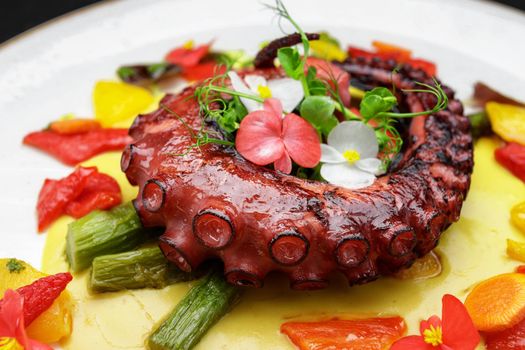 Cooked octopus tentacle close up with herbs and flowers