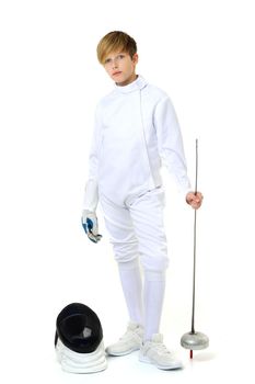 Boy in fencing costume posing with sabre and mask. Portrait of handsome teenage boy fencing player wearing white uniform standing with foil against white background.