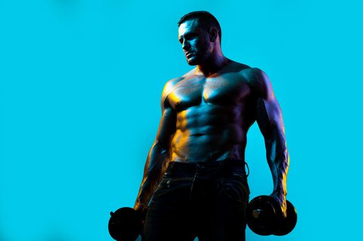 Exercise for the muscles biceps. Muscular bodybuilder guy doing exercises with dumbbells isolated on blue neon