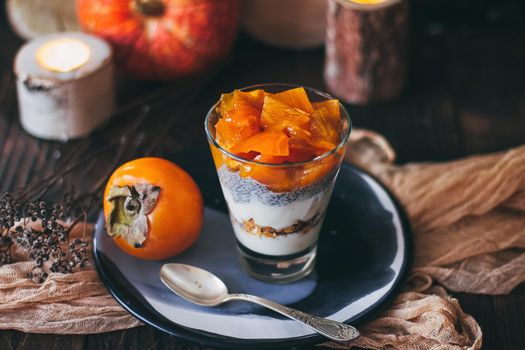 Delicious breakfast: chia seed pudding and persimmon close up in a glass on the table. horizontal.