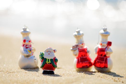 Positive sandy Snowman and Christmas Santa Claus at sunny tropical beach. New Year travel
