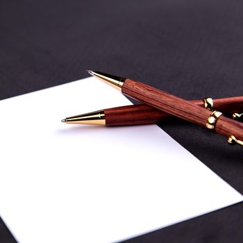 Luxury pen and mechanical pencil in wood and gold with a white sheet of paper.