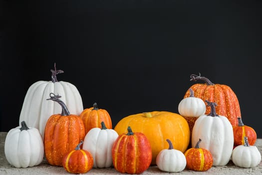 Composition of fresh pumpkins of various sizes and colors placed on table on Halloween day against black background