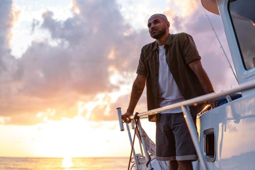 Young african american man relaxing on a sailboat in open sea at sunset, close up