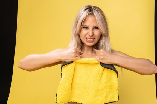 Girl rips rag with her hands yellow on a yellow background beautiful blonde rag tidy cleanup, home protective hygiene tile detergent, cleaner domestic. copy cleanly, hand around duties