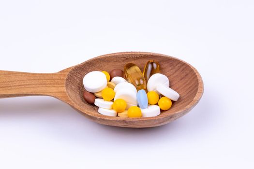 Medicine, pills and drug in wood spoon on white background with copy space.