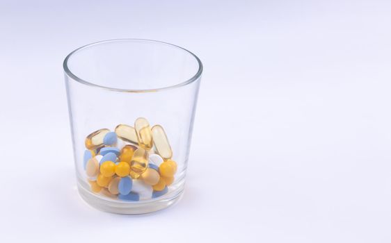 Dose of the colored pills in the glass of the package of pills. On white background with copy space for text.