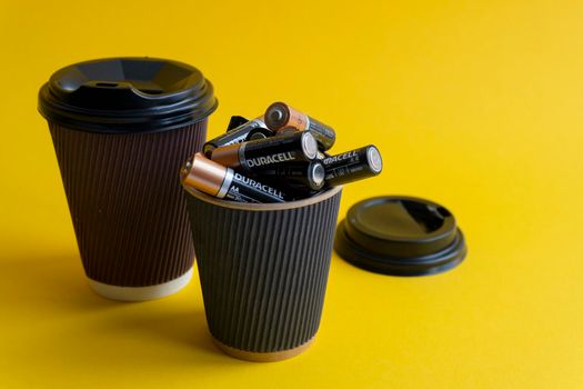 Kiev, Urkaine, 16 June 2020, Duracell AA batteries are in coffee takeaway cup with plastic lid and another cup with coffee to go,association of energy, yellow background,creative idea,space for text.