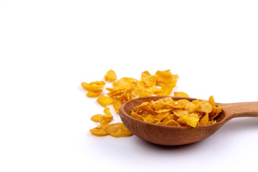 Crunchy corn flakes, cereal, muesli pile in wooden spoon isolated on white background.