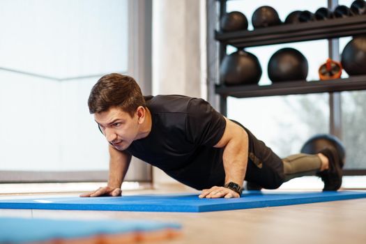 Young athletic man doing push-ups in a gym, close up photo