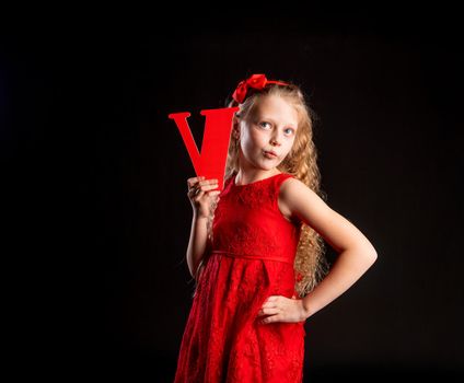V holds a child holding in his hand the letter LOVE love red, Valentine's Day, on the floor hearts of a wonderful romance. Inspiration. dream feeling, heart in red girl dress, barefoot