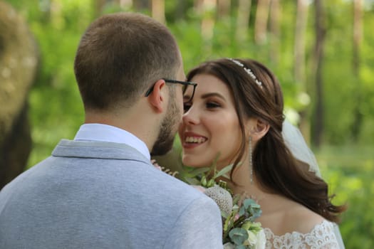 Wedding photo of the bride and groom in a gray-pink color on nature in the forest and rocks