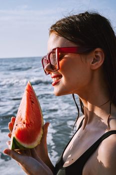 woman in black swimsuit with watermelon by the ocean. High quality photo