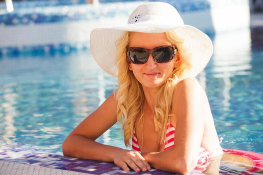 Blonde woman in hat at the swimming pool
