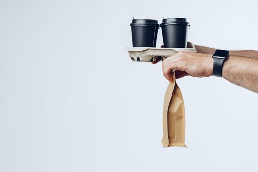 Courier hands giving packed food delivery close up against grey background