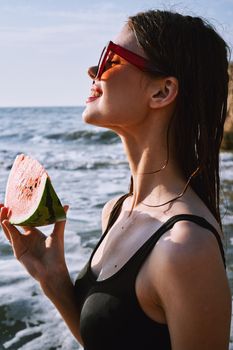 woman in black swimsuit with watermelon by the ocean. High quality photo