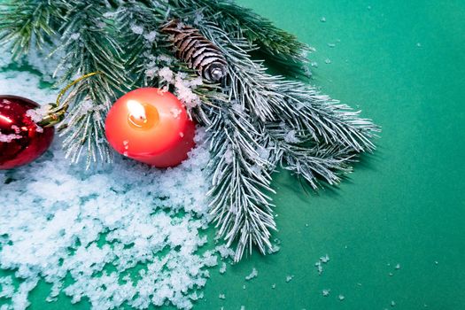 New year and christmas concept. There are candle, pine branches and snow on green background. View from the top.