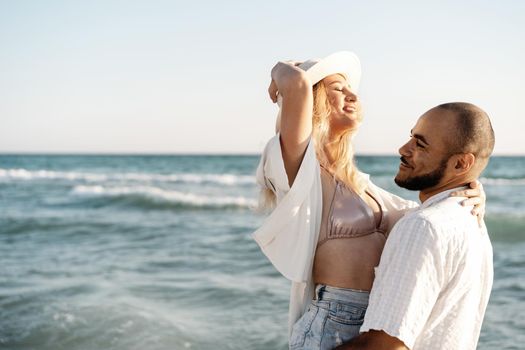 Beautiful young couple hugging on the beach by the water, close up