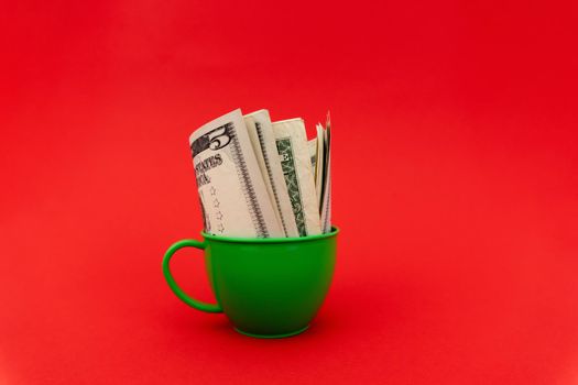 Five dollars in green cup at red background. Enough space for text.