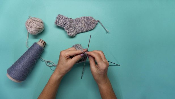 Close up of the process of knitting socks with gray and white threads. Woman is knitting socks.