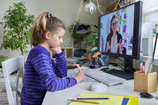 Young child girl studying with teacher remotely on computer using video call, an individual online lesson, videoconference application. Education, technology, children, pre-teens, e-learning concept