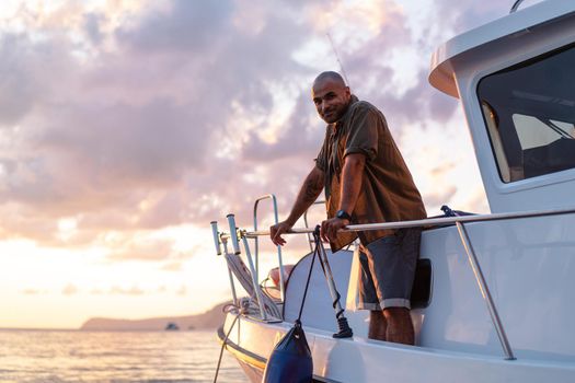 Young african american man relaxing on a sailboat in open sea at sunset, close up