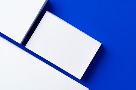 Blank white businesscards on classic blue background, copy space