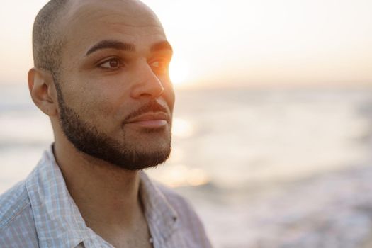 Portrait of a handsome young american man during sunset at the beach, close up