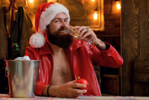 Bearded handsome man, Santa Claus with beard smile and drink champagne. Christmas lights garland. Merry christmas and happy new year
