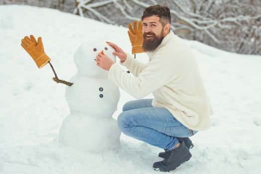 Funny man playing with snowman in winter park. Merry Christmas and Happy New Year Holidays