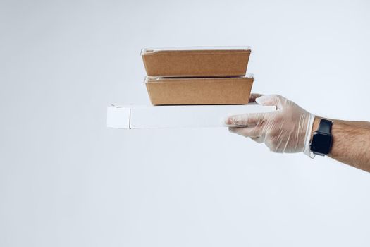 Courier hands in latex gloves giving packed food delivery close up