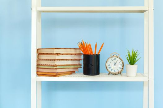 White metal rack with books against blue background. Close up.