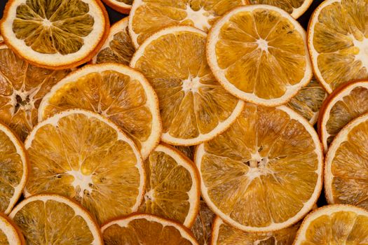 Close up of sliced dried oranges, many slices of tangerines, as background or texture, view from the top, tasty homemade decor and snacks, macro image