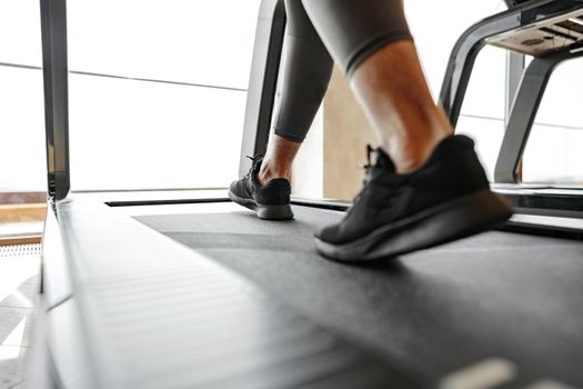 Close up photo of male legs running in a gym on a treadmill