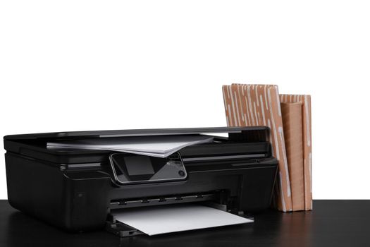 Office table with laser printer and books against white background, close up