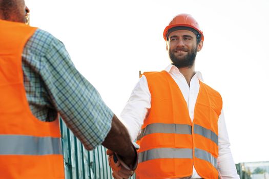 Close up photo photo of two men builders in workwear shaking hands