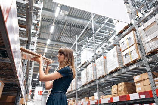 Wholesale warehouse. Beautiful young woman worker of store in shopping center. Girl looking for goods with a tablet is checking inventory levels in a warehouse. Logistics concept.