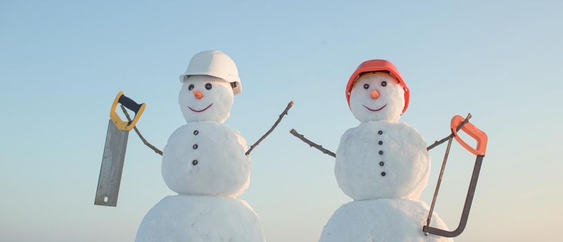 Snowman builder in winter in helmet. Christmas snow man, building and repair work