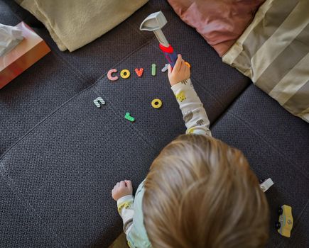 Covid-19, Corona virus. A little boy hammers the CORONA letters with a hammer away, a symbol for fighting back against the world menacing infection menace