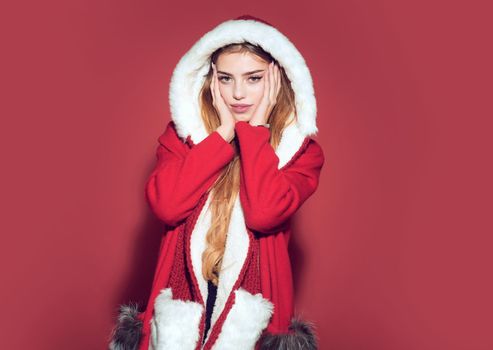 Christmas woman in red hat. Happy girl celebrate new year on red background. Xmas party and winter holiday. Woman in santa costume with pretty face.
